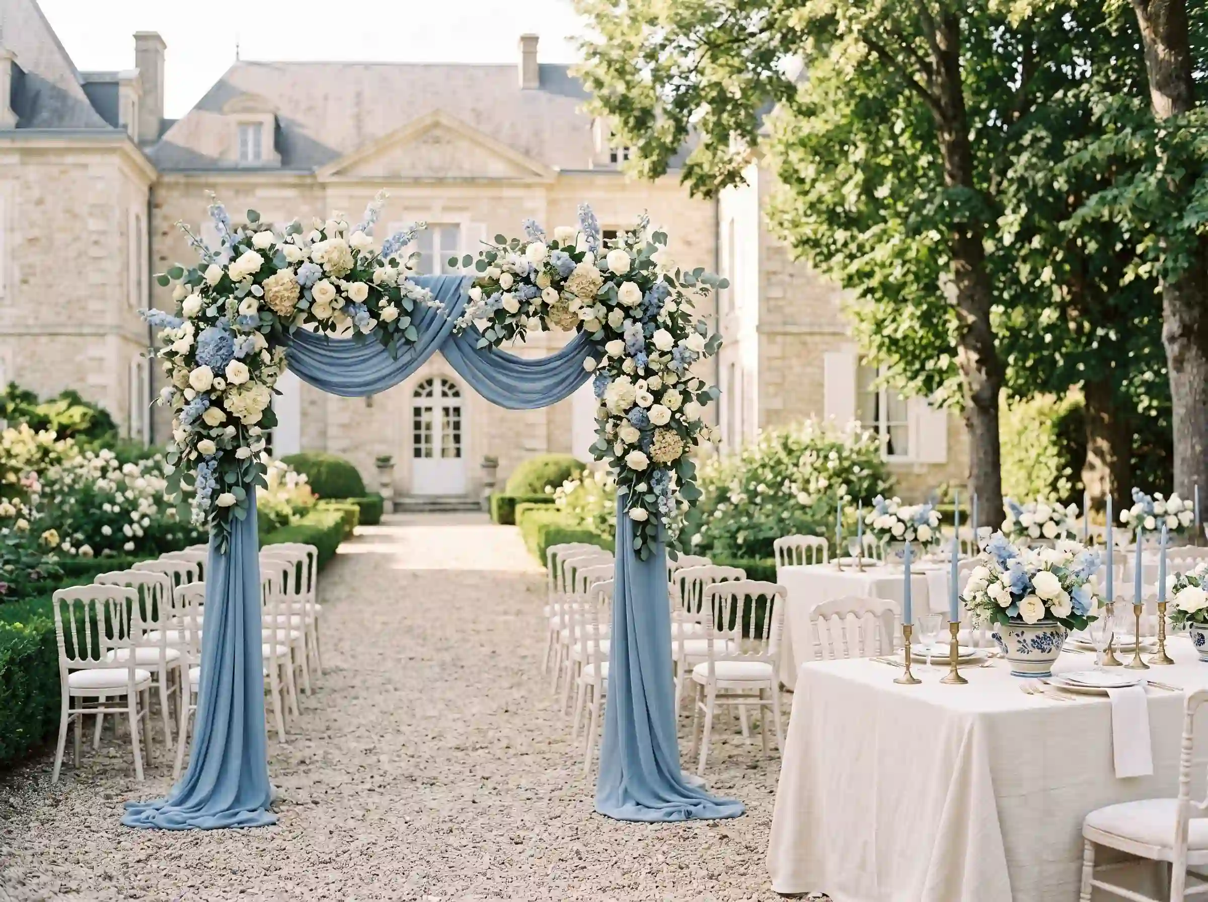 French chateau wedding with blue draped ceremony arch and cream floral arrangements