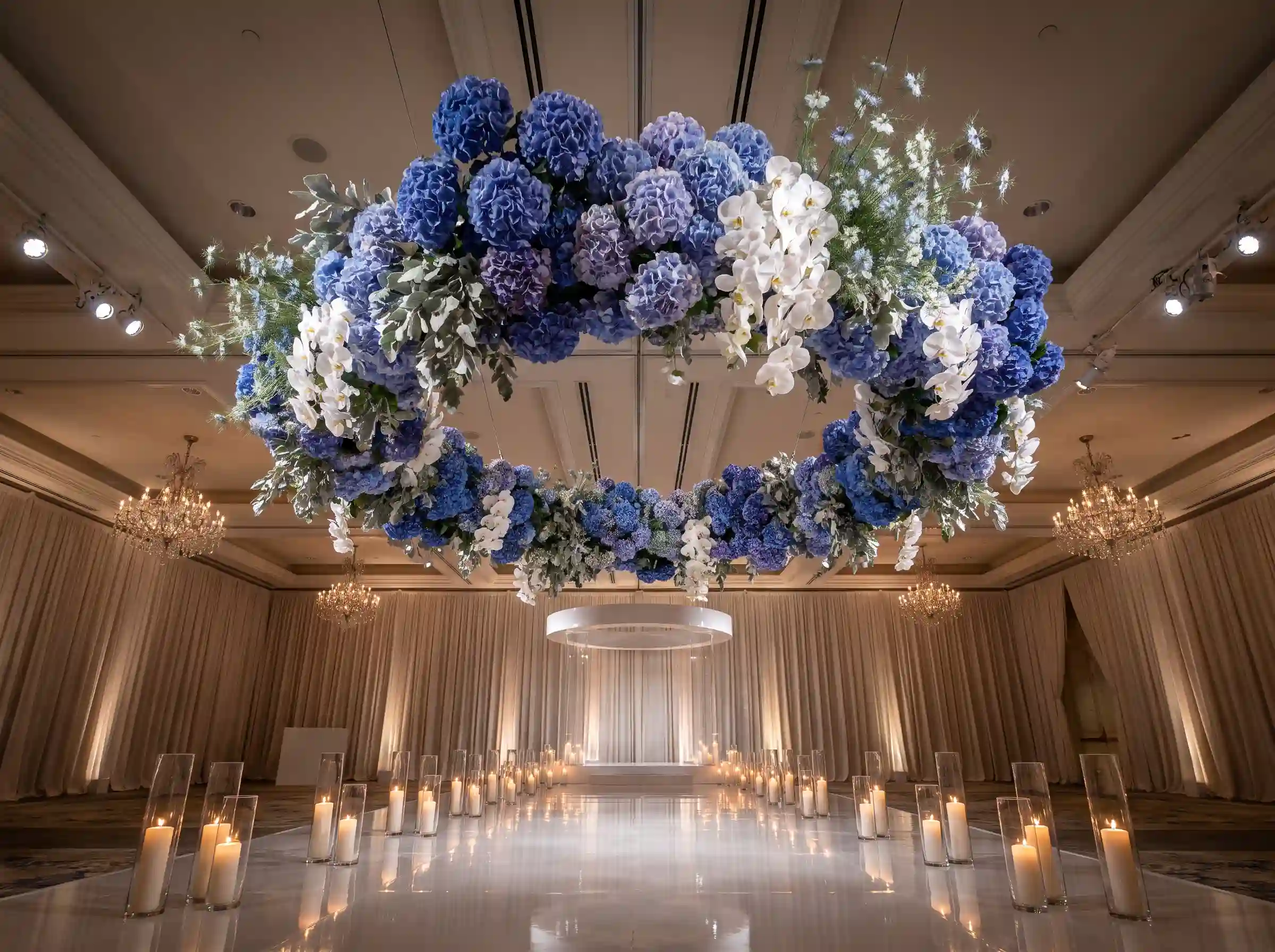 Suspended floating cloud of deep blue hydrangeas with white orchids above an indoor wedding ceremony space
