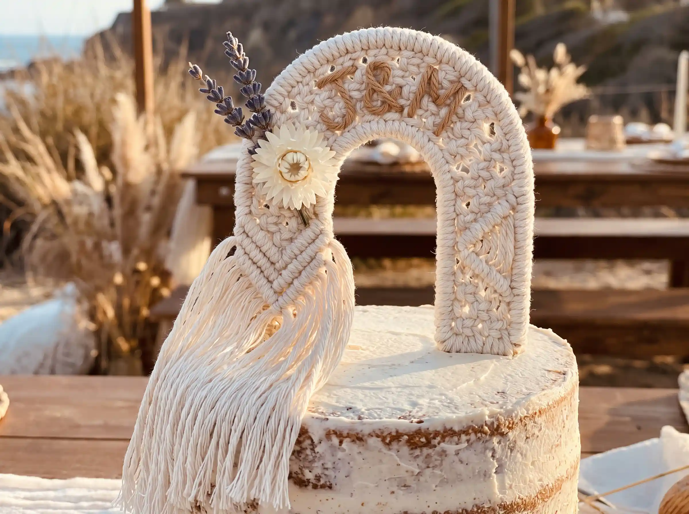 Handwoven macramé arch cake topper with initials, dried lavender and strawflower on naked wedding cake