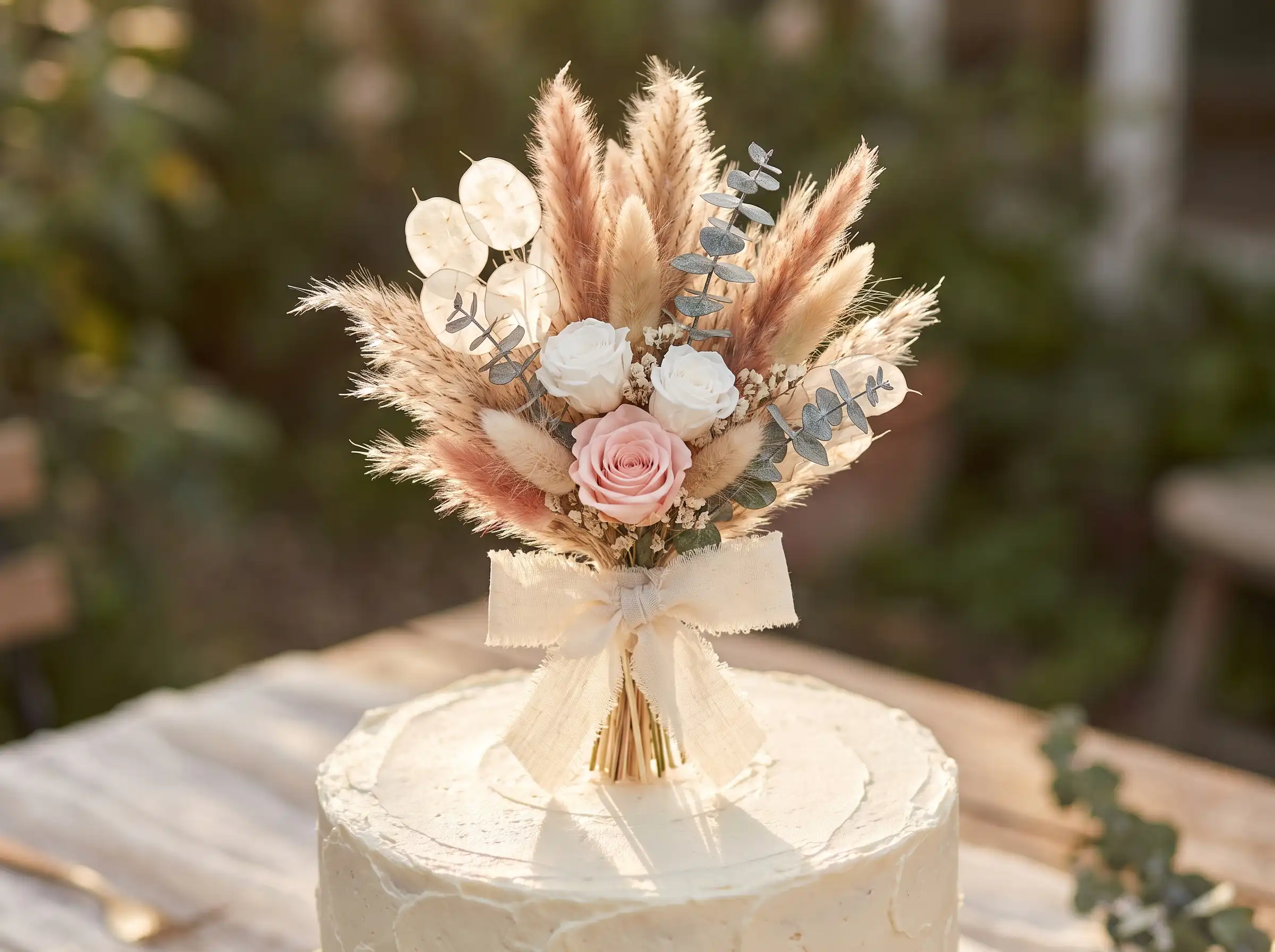 Mini dried pampas bouquet cake topper with roses eucalyptus and linen bow on white buttercream cake