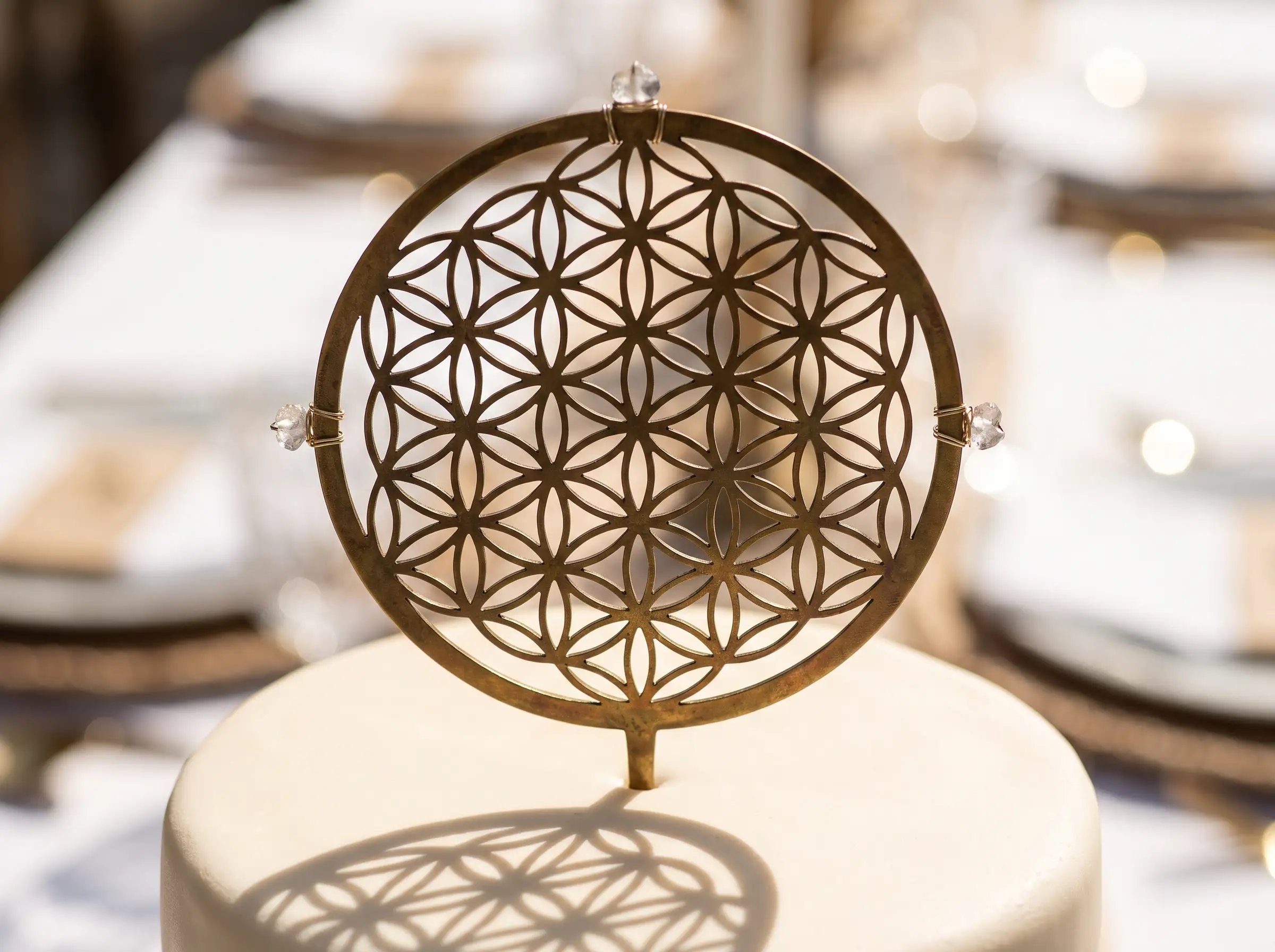 Gold flower of life sacred geometry cake topper with clear crystals casting shadow on white cake