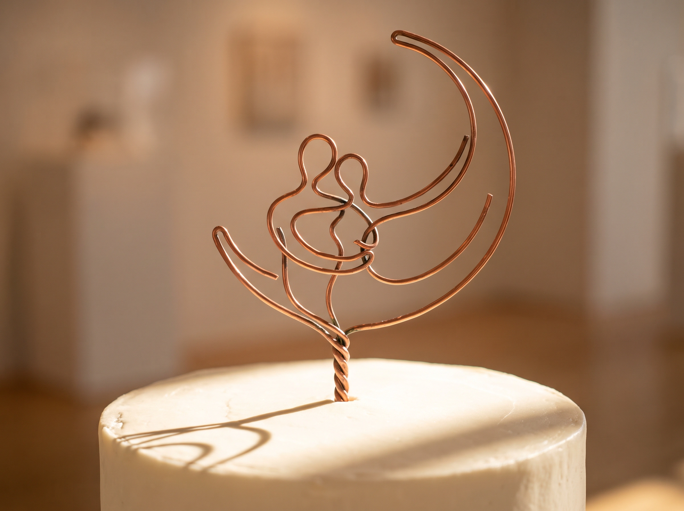 Rose gold wire sculpture cake topper of embracing couple under crescent moon on white cake