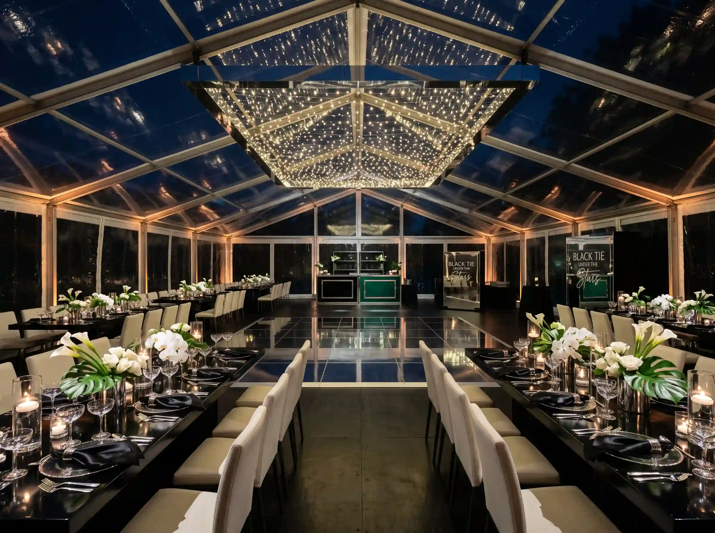 Black tie reception under transparent tent with starry night sky and mirrored dance floor in silver and emerald