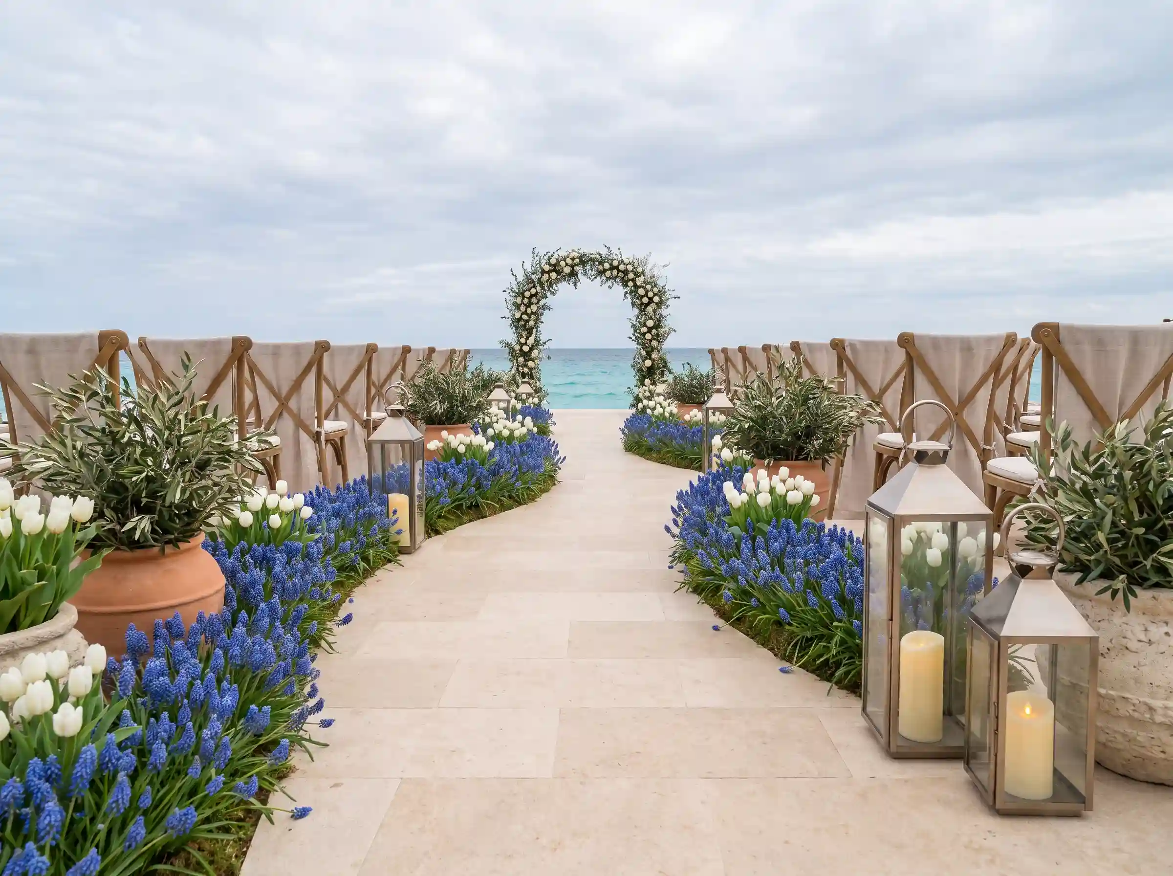 Dense ribbons of ocean blue muscari lining a curved wedding ceremony aisle with white tulips and limestone planters