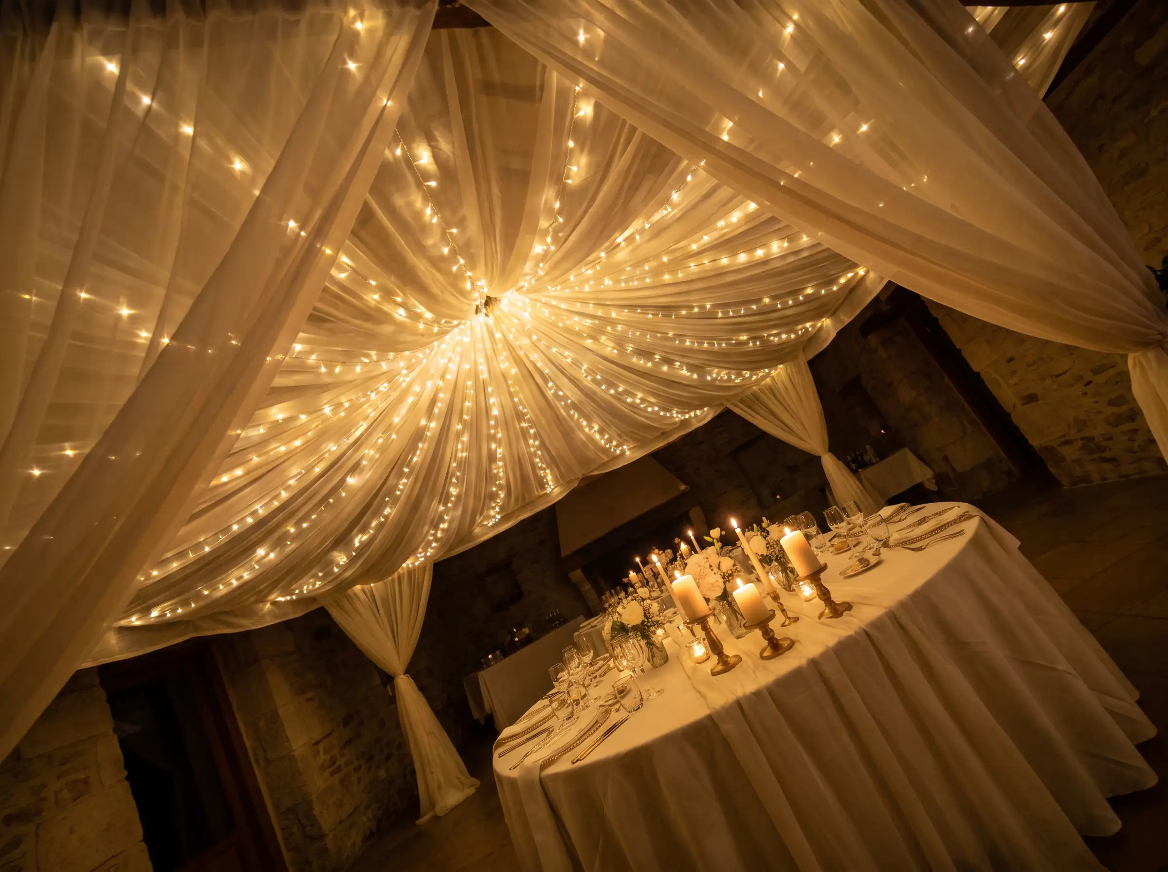 Starfield canopy of fairy lights suspended over a wedding dinner table creating a glowing ceiling