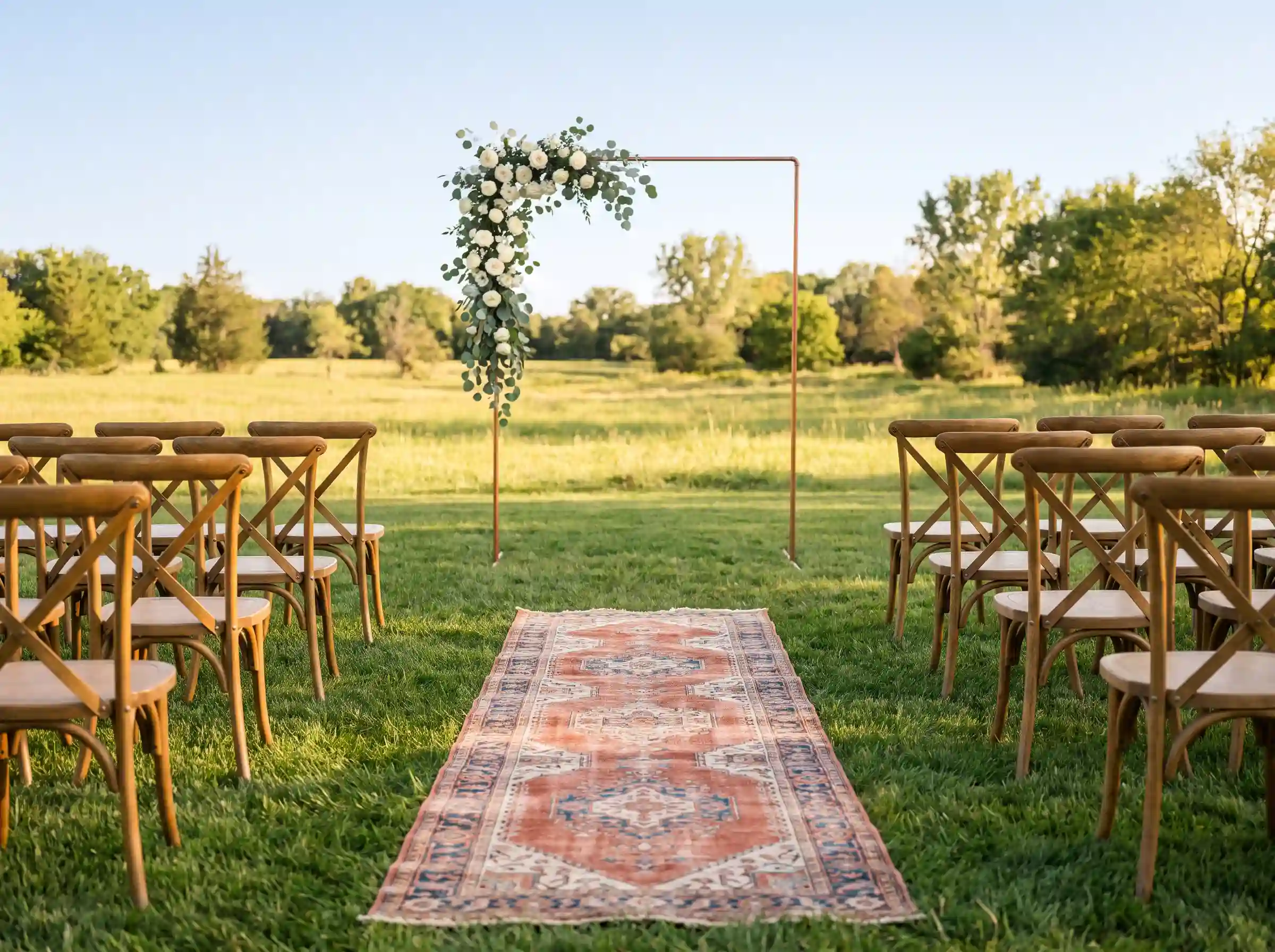 Vintage Persian rug in terracotta and jewel blue used as outdoor ceremony aisle runner on green grass