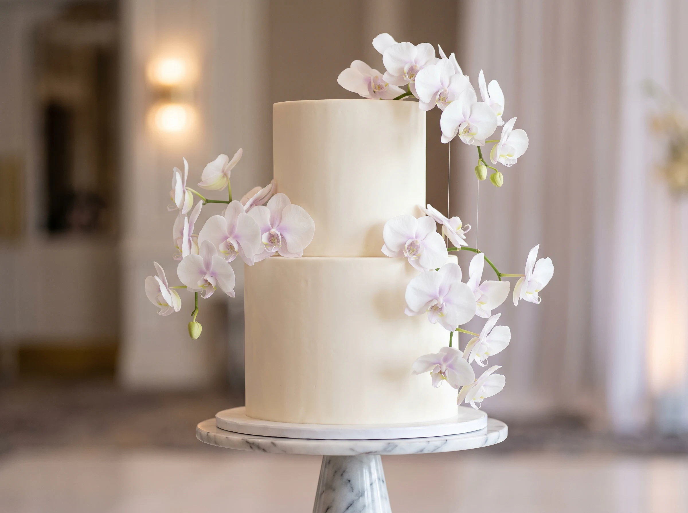 Modern luxurious two-tier wedding cake with floating orchid blooms and sleek white finish