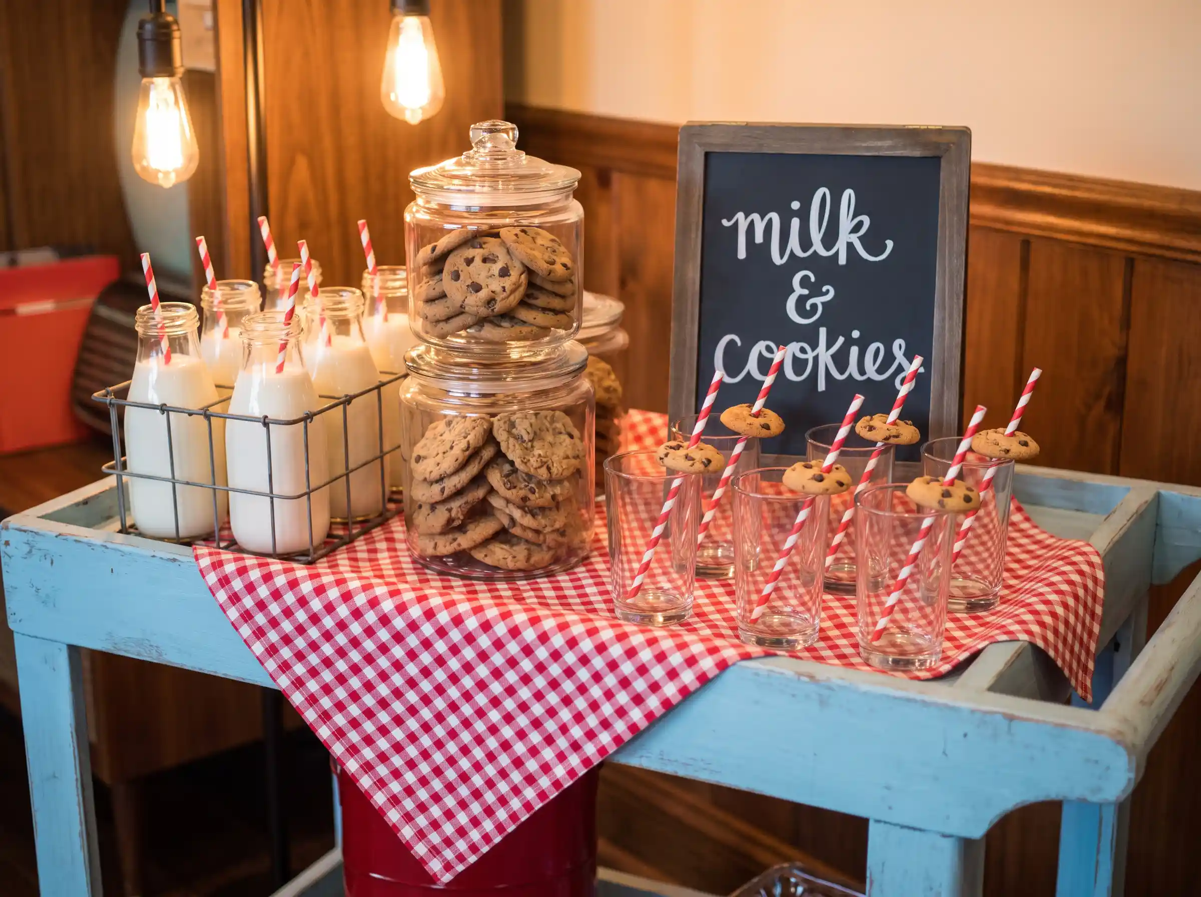 Vintage powder blue cart with glass milk bottles cookie jars red gingham runner and chalkboard milk and cookies sign